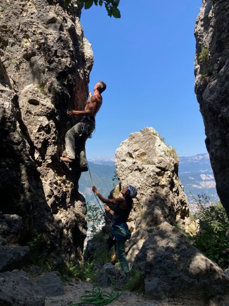 Arrampicatore in parete con il compagno di cordata in sicura, falesia in Trentino